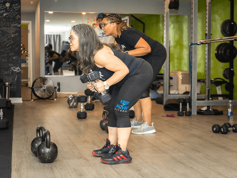 women over 40 working out at a group fitness class performing bent over bicep extensions