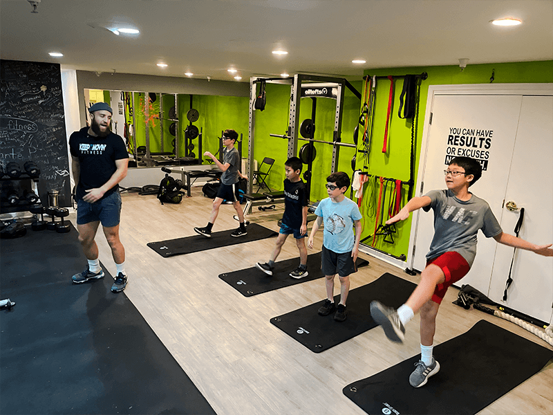 youth fitness groups build confidence and skill with lead trainer Dante puchala showing four boys how to perform a warm-up exercise